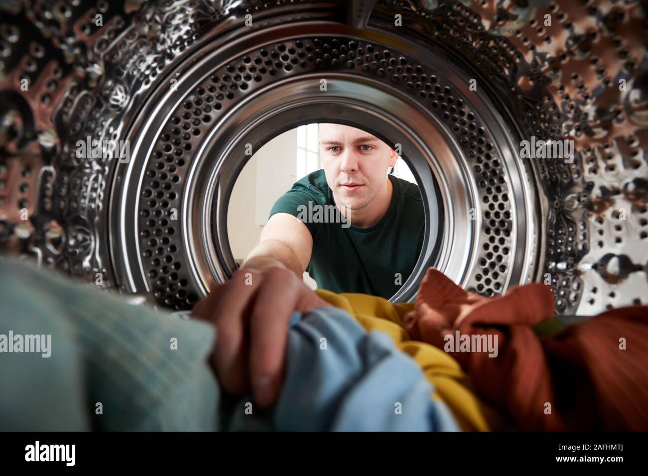 View Looking Out From Inside Washing Machine As Young Man Does Laundry Stock Photo