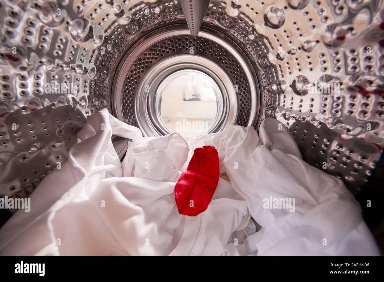 View Looking Out From Inside Washing Machine With Red Sock Mixed With White Laundry Stock Photo