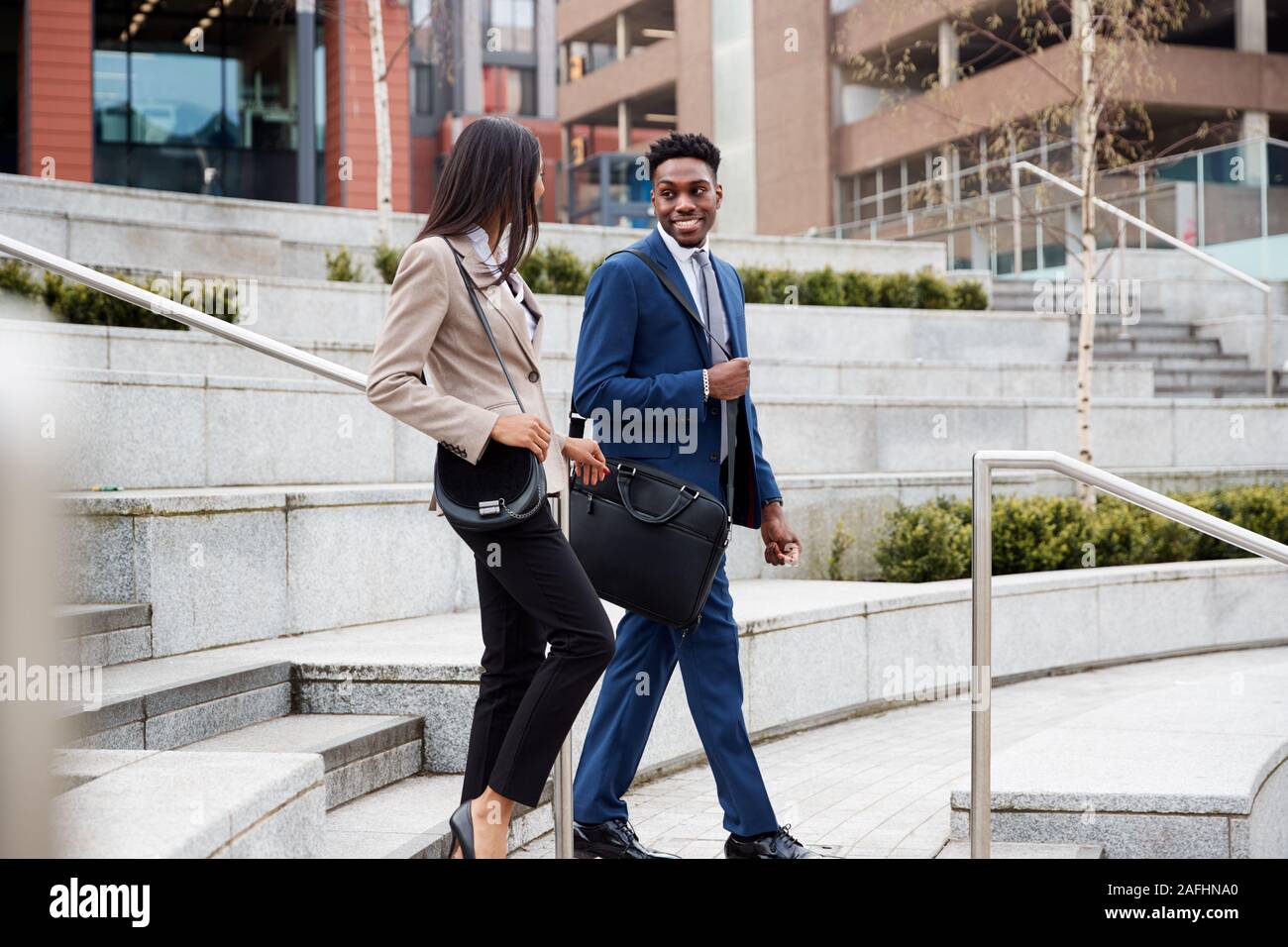 Businessman And Businesswoman Commuting To Work Walking Down Steps Outside Office Building Stock Photo