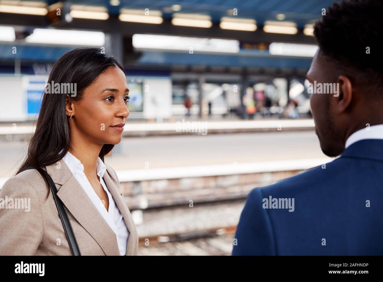 Businessman And Businesswoman Commuting To Work Talking On Railway Platform Waiting For Train Stock Photo