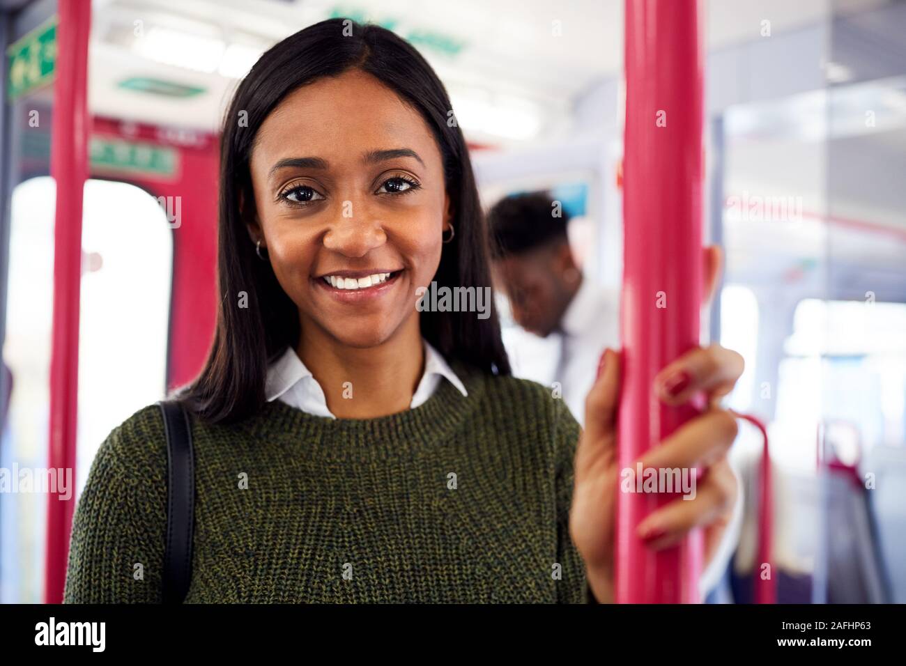 Portrait Of Smiling Female Passenger Standing By Doors In Train Stock Photo