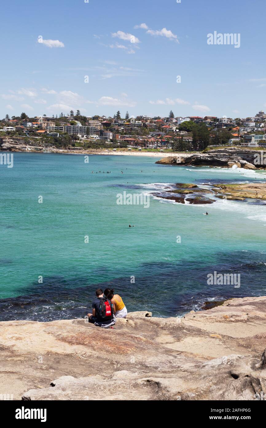 Sydney travel; A couple sitting on the coast overlooking Tamarama and Bronte Beaches, Sydney New South Wales, Australia Stock Photo