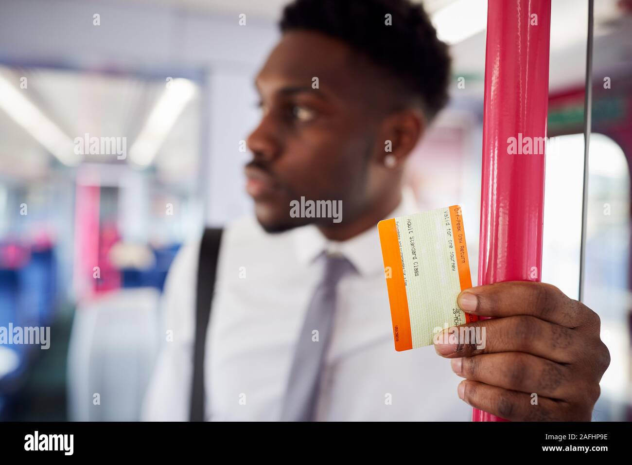 Businessman Standing In Train Commuting To Work Holding Ticket Stock Photo