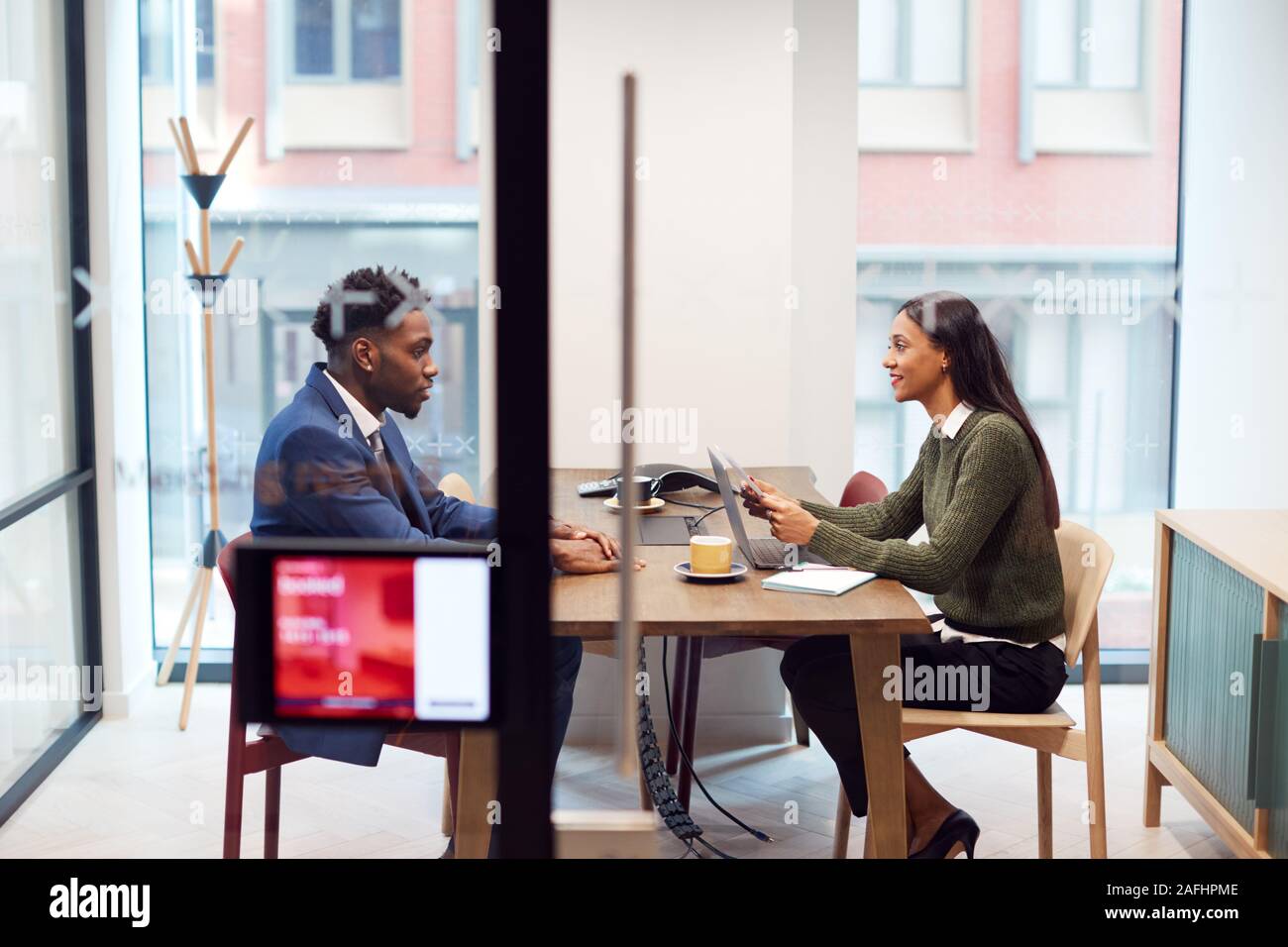 Businesswoman Interviewing Male Job Candidate In Meeting Room Stock Photo
