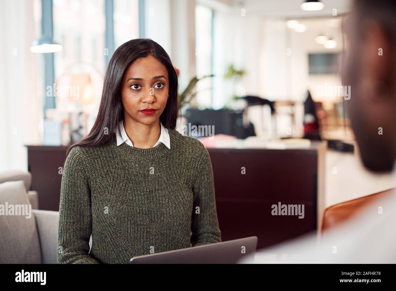 Businesswoman Interviewing Male Job Candidate In Seating Area Of Modern Office Stock Photo