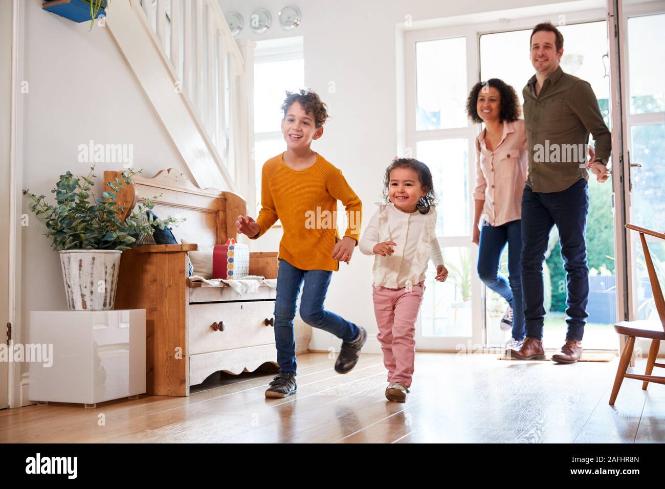 Family Returning Home After Trip Out With Excited Children Running Ahead Stock Photo