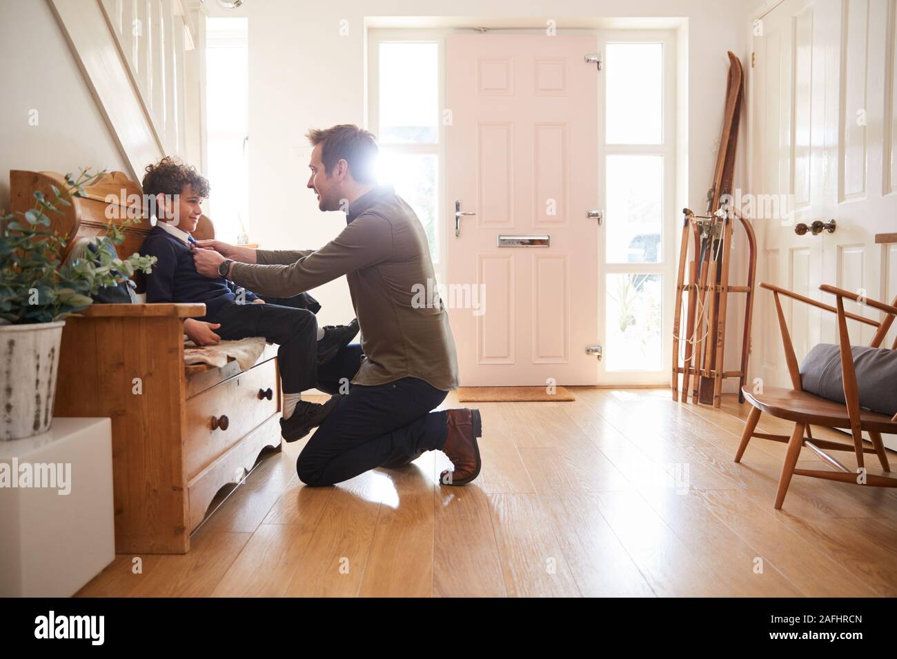 Single Father At Home Getting Son Wearing Uniform Ready For First Day Of School Stock Photo