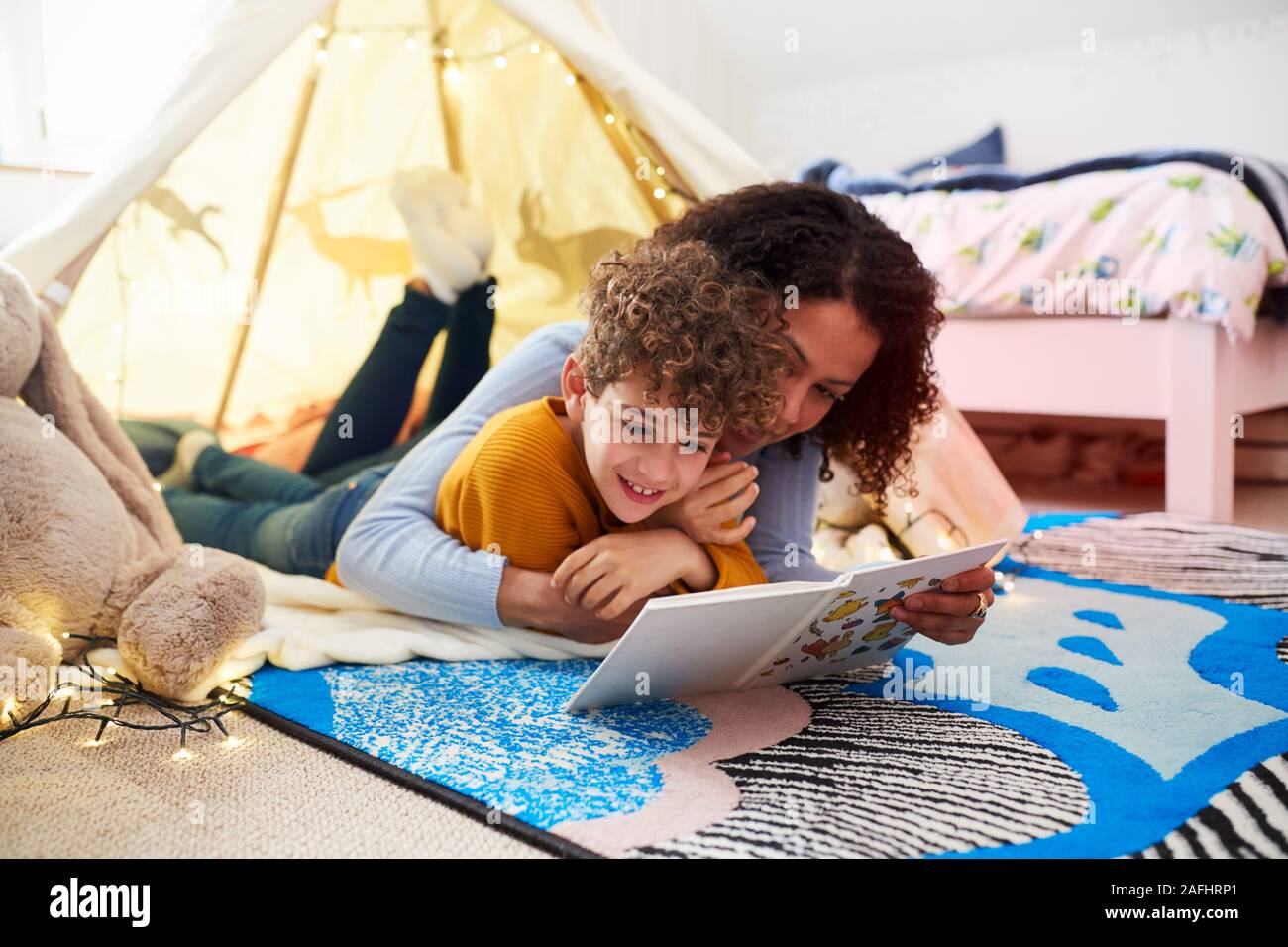 Single Mother Reading With Son In Den In Bedroom At Home Stock Photo