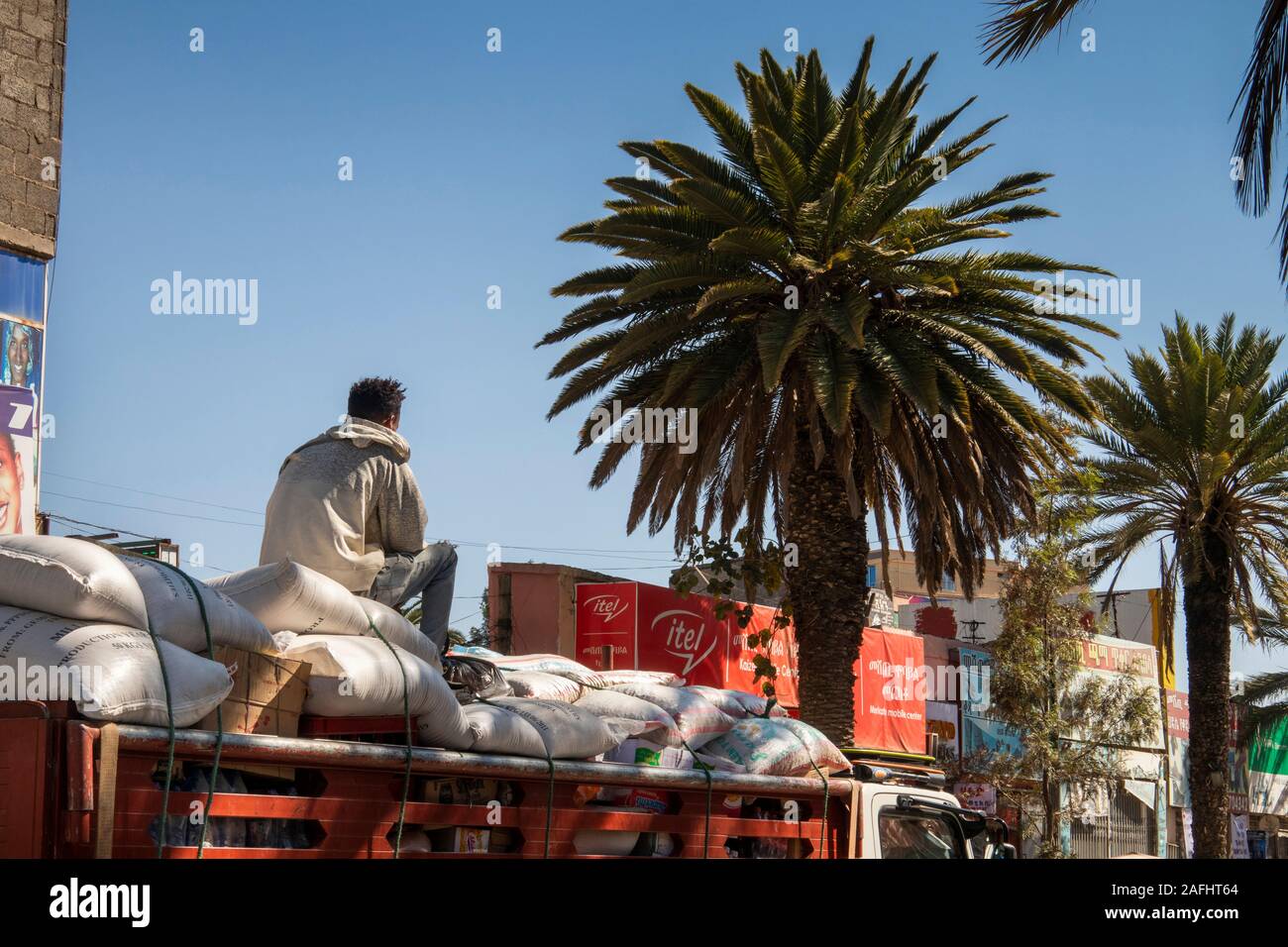 Ethiopia, Tigray, Mekele, city centre, Hahefen St, man sat on top of sack-laden truck passing shops Stock Photo