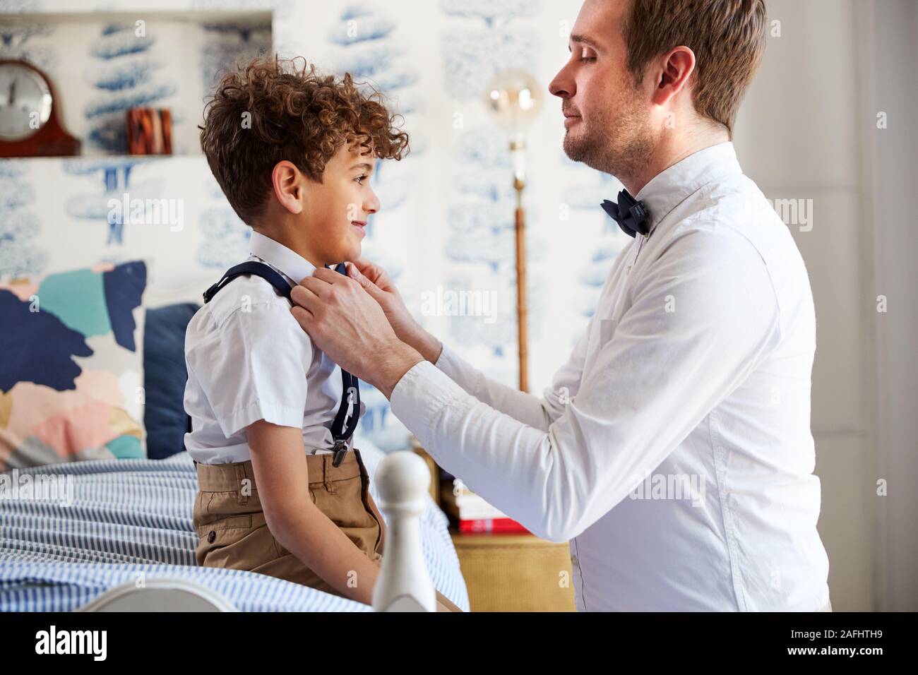 Father And Son Wearing Matching Outfits Getting Ready For Wedding At Home Stock Photo