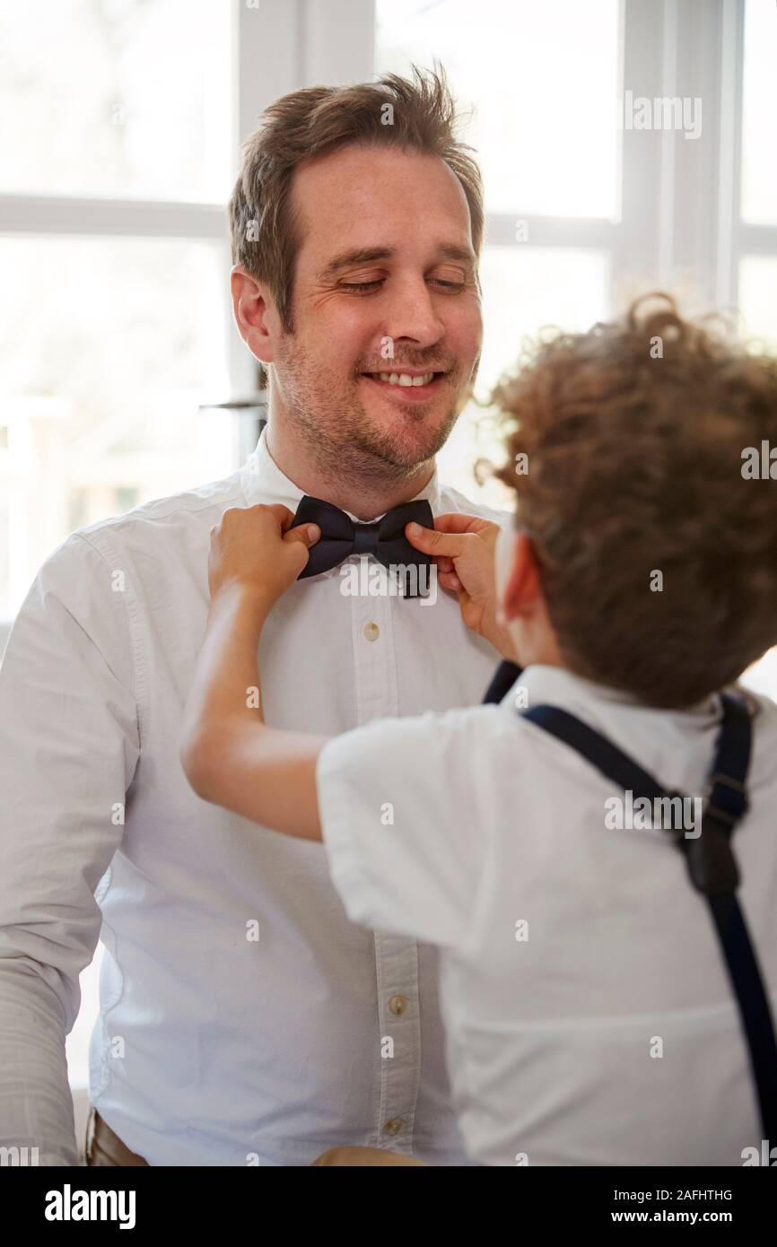Father And Son Wearing Matching Outfits Getting Ready For Wedding At Home Stock Photo