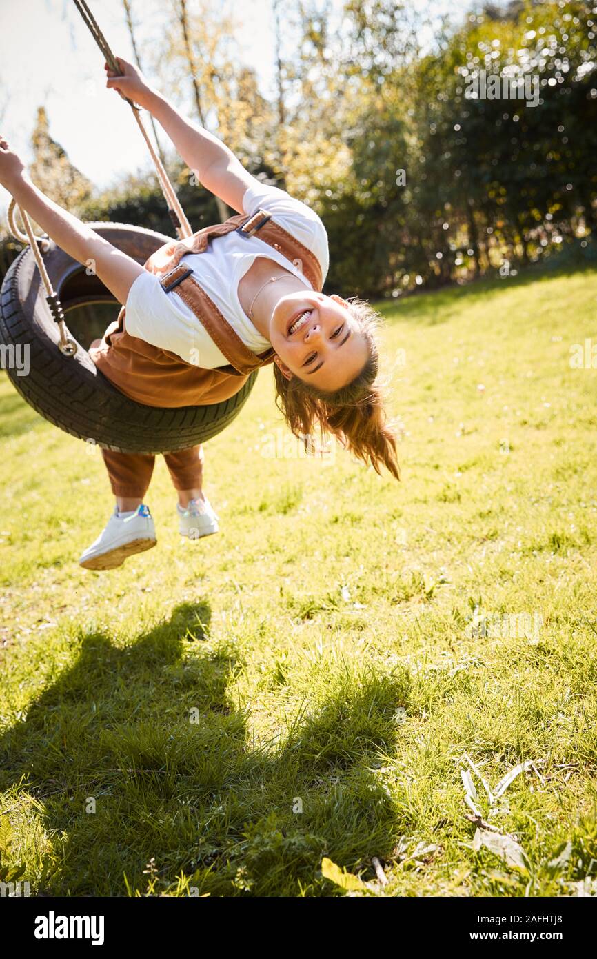 Portrait Of Girl Having Fun On Tyre Swing In Garden At Home Stock Photo