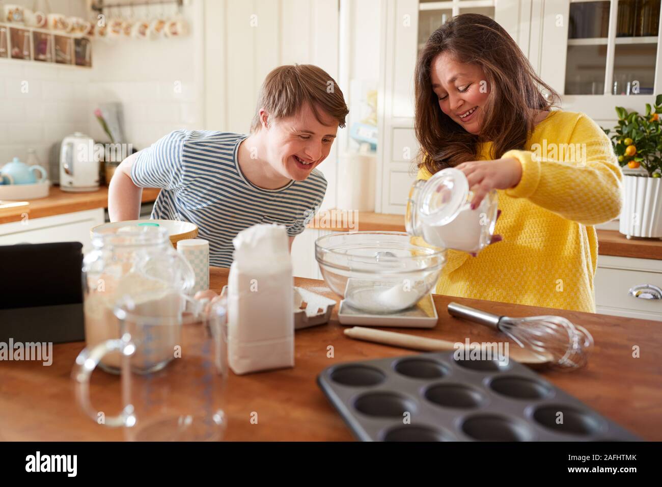 Young Downs Syndrome Couple Baking In Kitchen At Home Stock Photo
