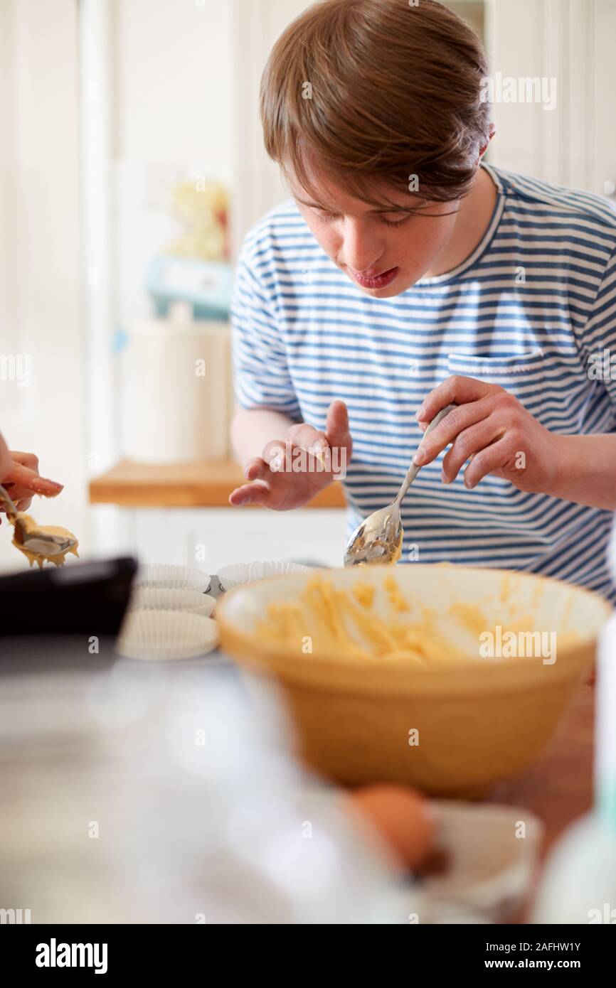 Young Downs Syndrome Man Baking Cupcakes In Kitchen At Home Stock Photo