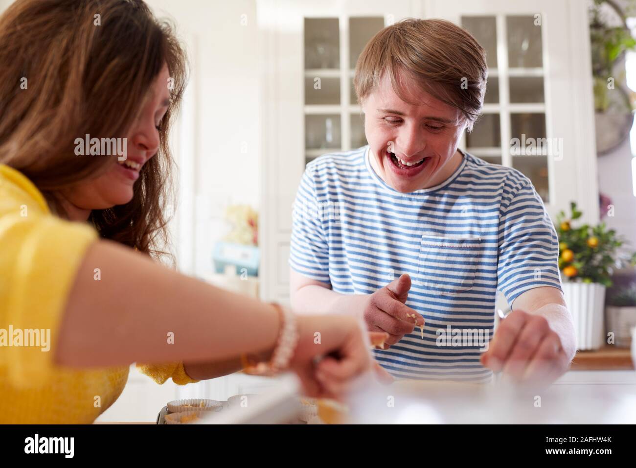 Young Downs Syndrome Couple Baking Cupcakes In Kitchen At Home Stock Photo