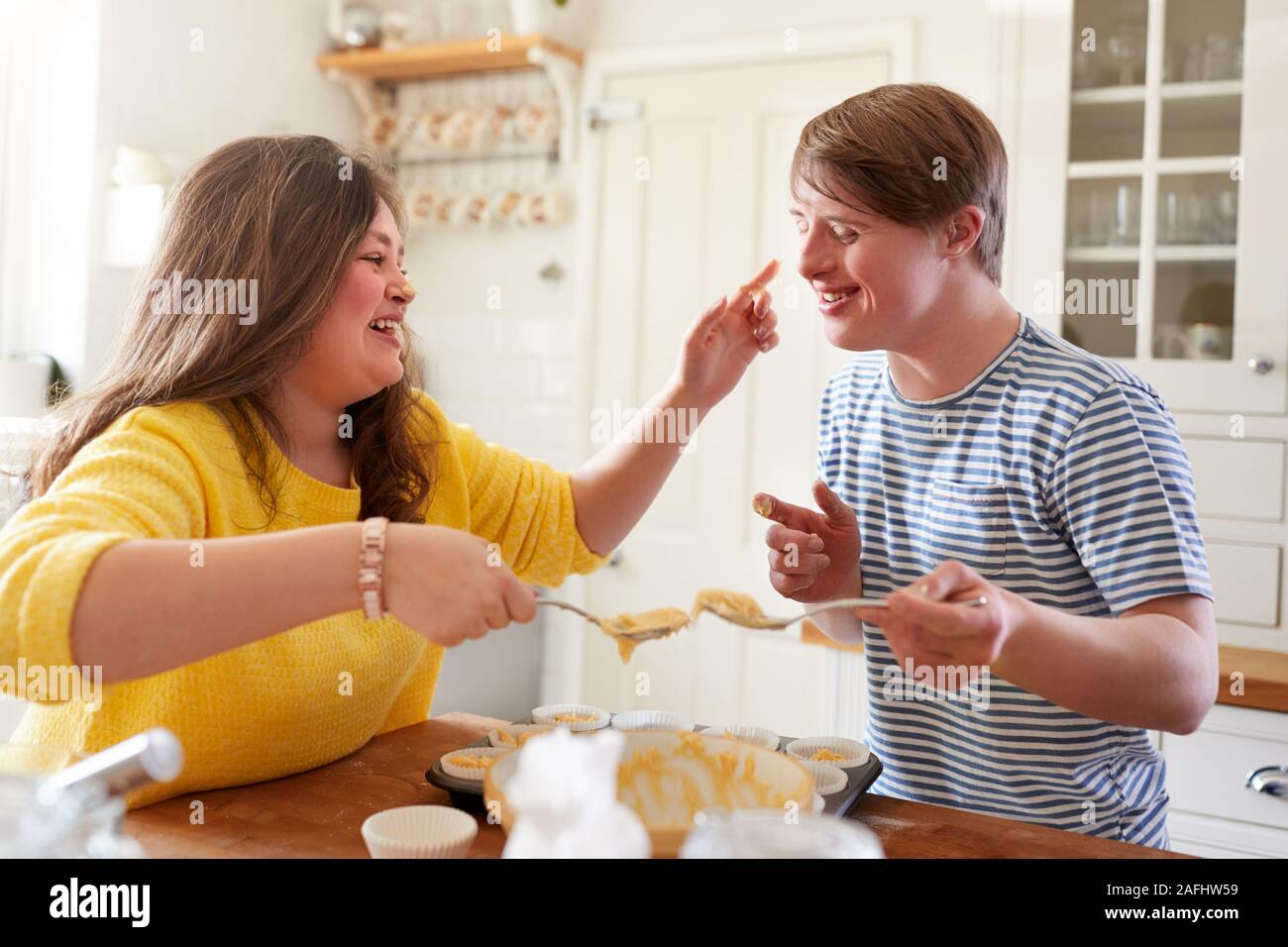 Young Downs Syndrome Couple Having Fun Baking Cupcakes In Kitchen At Home Stock Photo