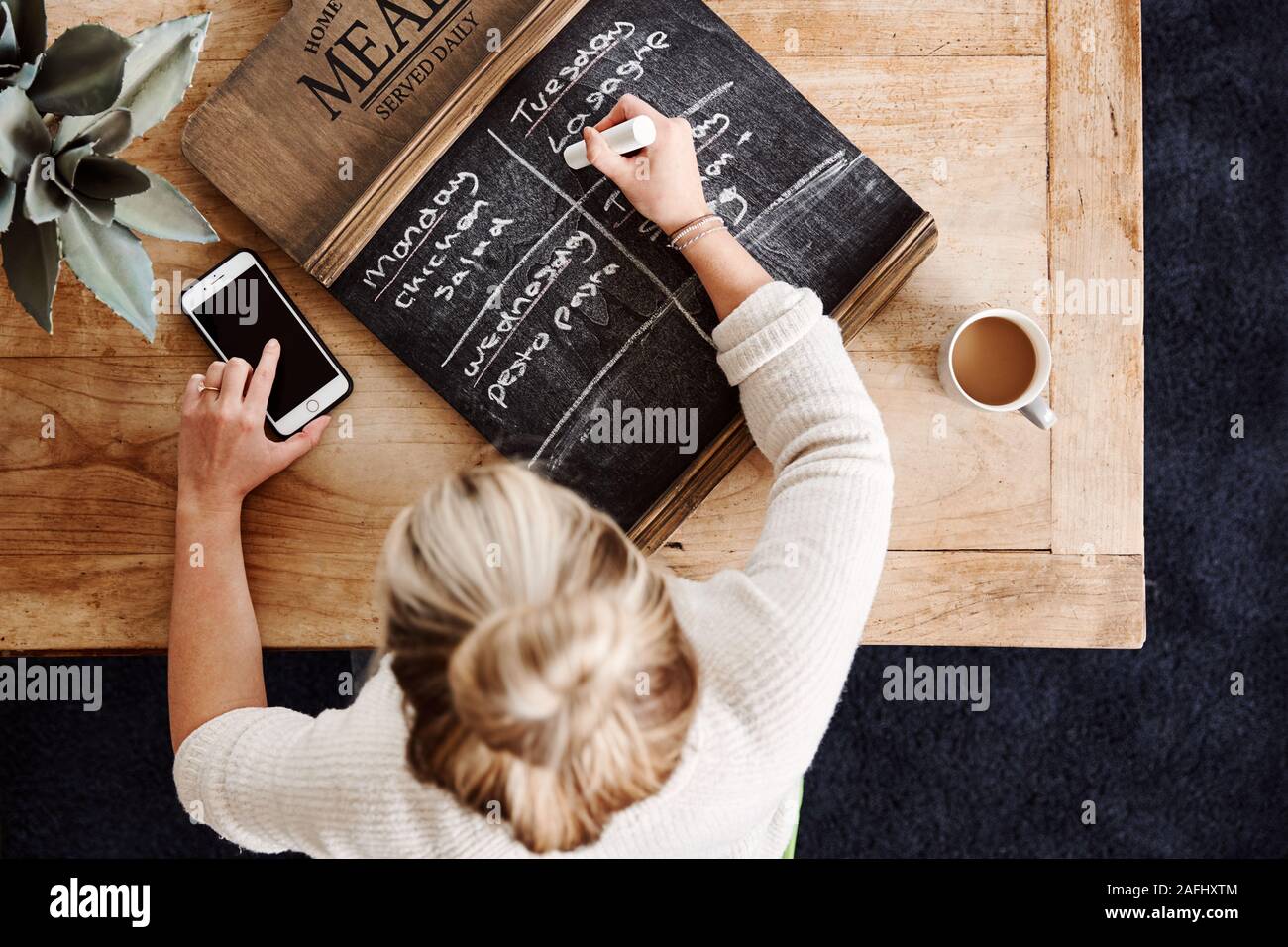 Overhead Shot Looking Down On Woman At Home Writing Meal Plan On Blackborad Stock Photo