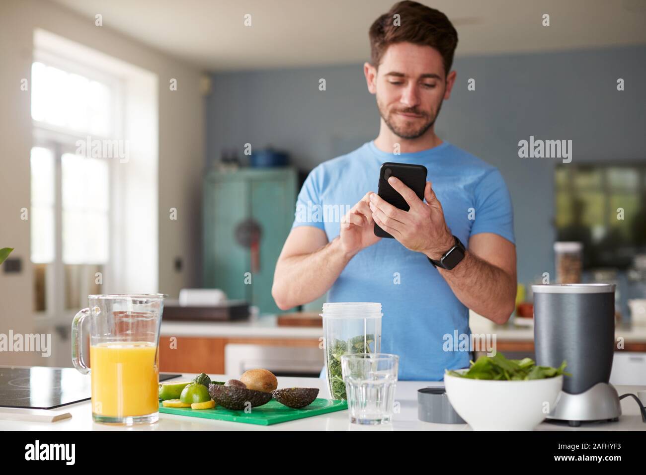 Man Using Fitness Tracker To Count Calories For Post Workout Juice Drink He Is Making Stock Photo