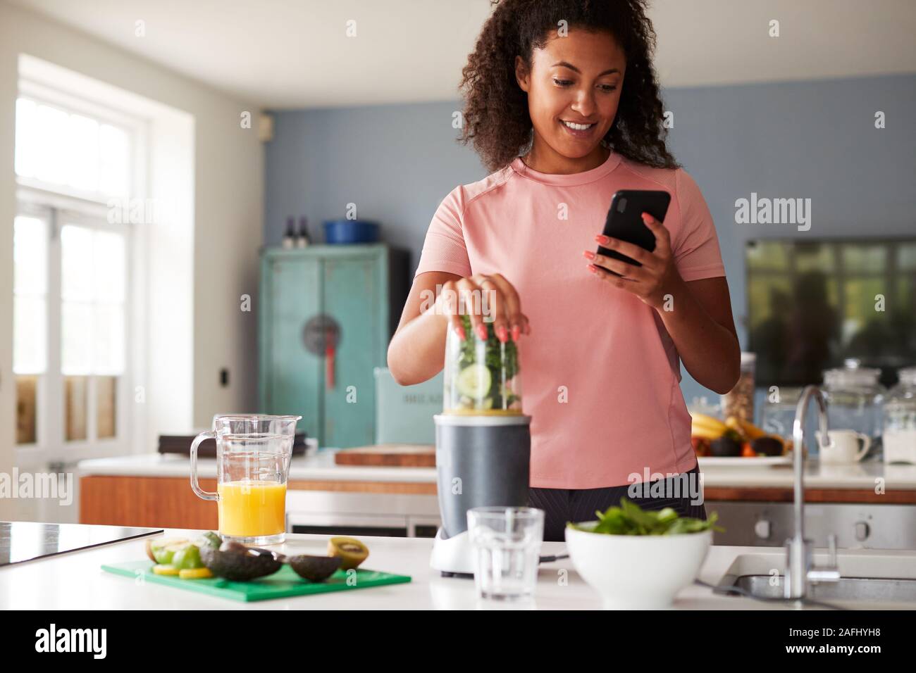 Woman Using Fitness Tracker To Count Calories For Post Workout Juice Drink He Is Making Stock Photo