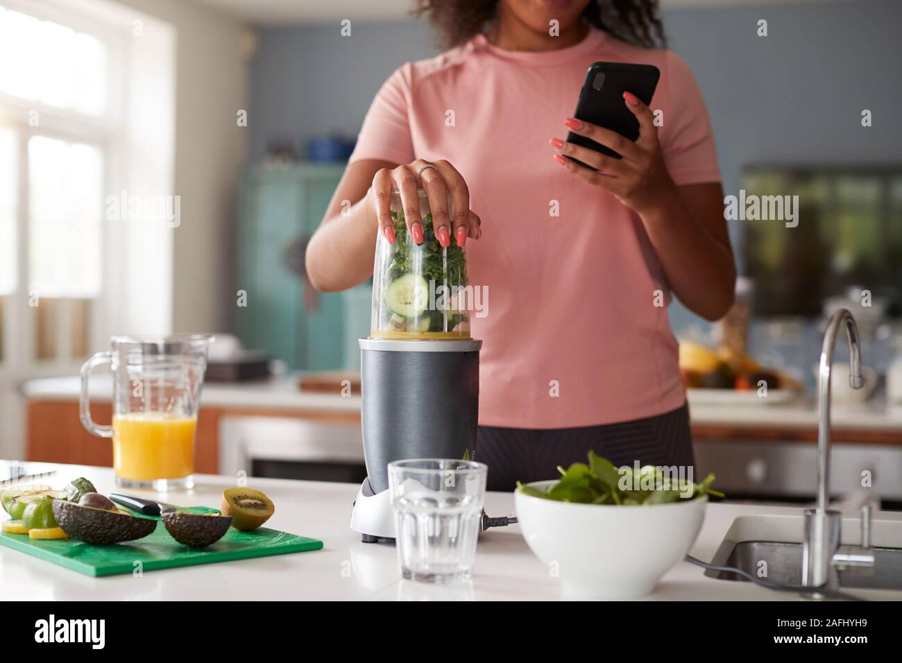 Close Up Of Woman Using Fitness Tracker To Count Calories For Post Workout Juice Drink She Is Making Stock Photo