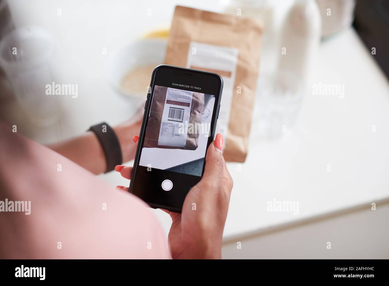 Woman Wearing Fitness Clothing Scanning QR Code On Food Packaging To Find Nutritional Information Stock Photo