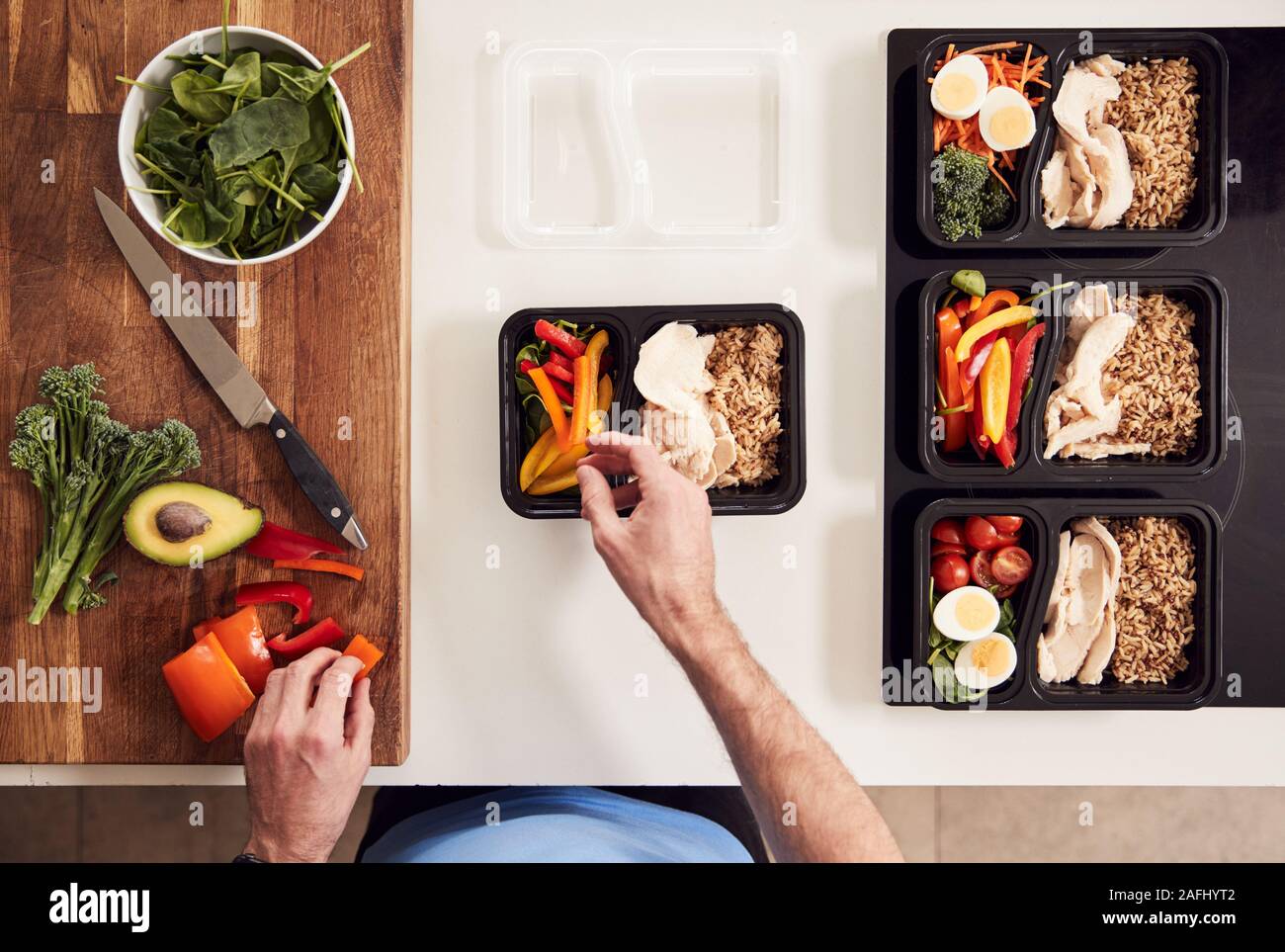 Overhead Shot Of Man Preparing Batch Of Healthy Meals At Home In Kitchen Stock Photo