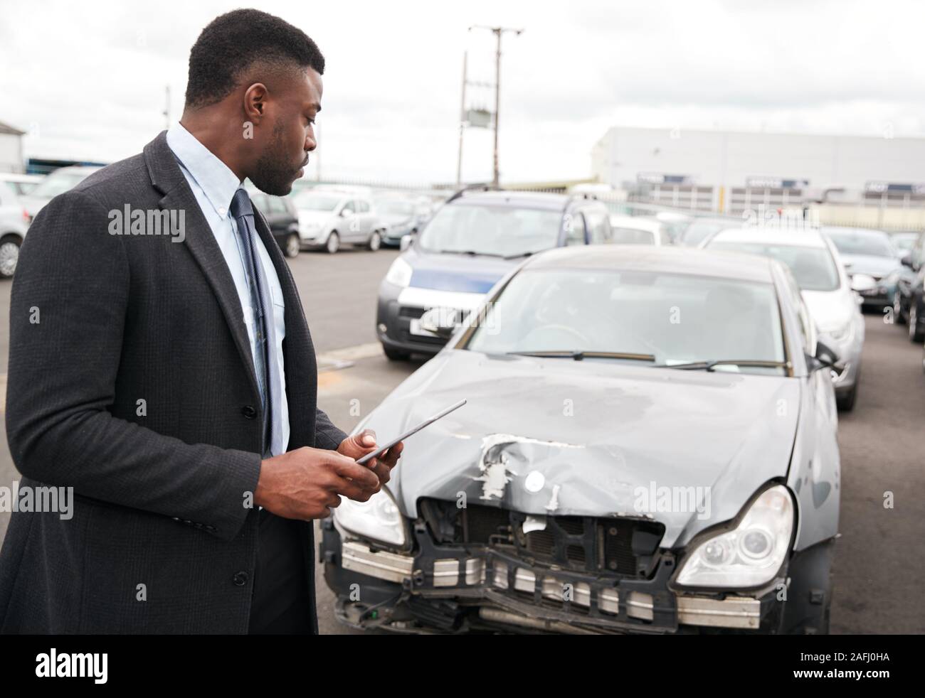 Male Insurance Loss Adjuster With Digital Tablet Inspecting Damage To Car From Motor Accident Stock Photo