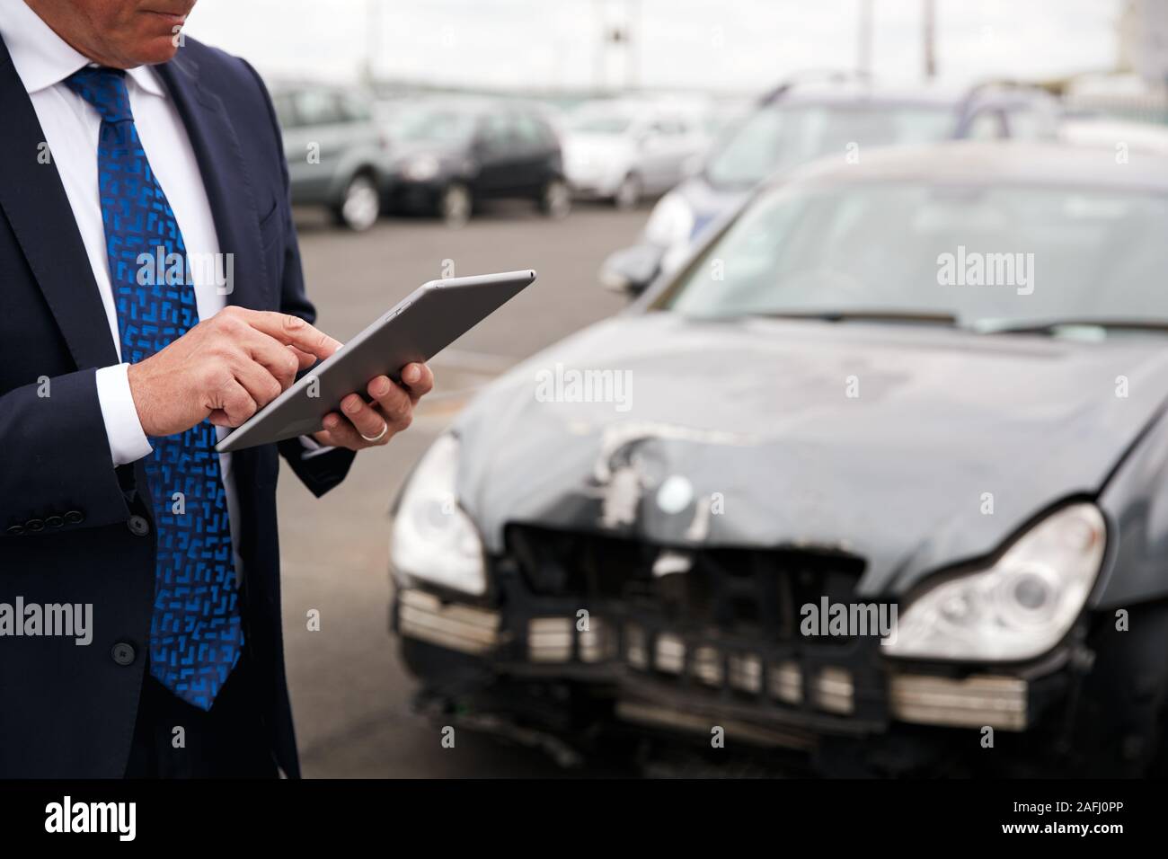 Male Insurance Loss Adjuster With Digital Tablet Inspecting Damage To Car From Motor Accident Stock Photo