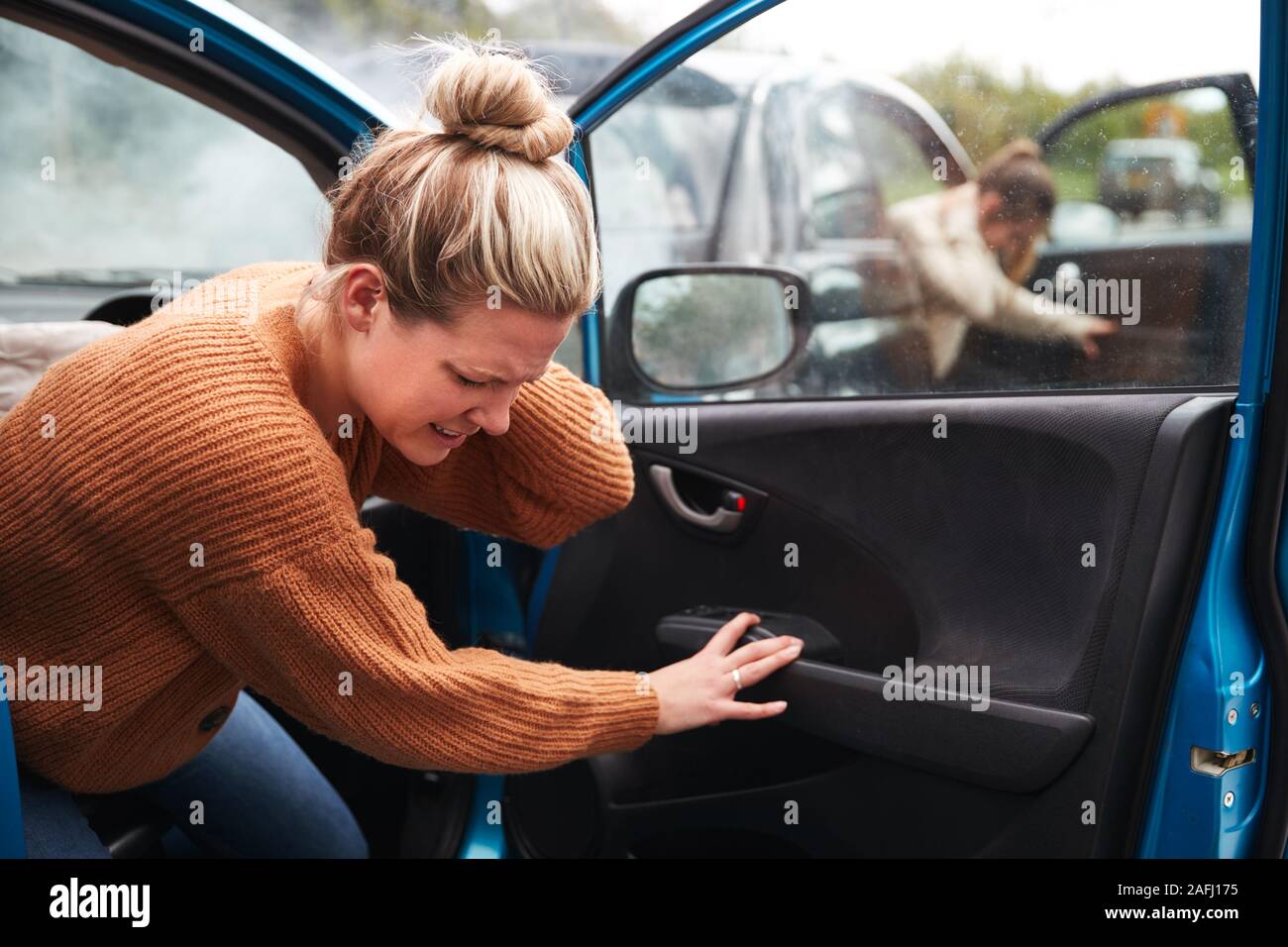 Female Motorist In Crash For Crash Insurance Fraud Getting Out Of Car Stock Photo