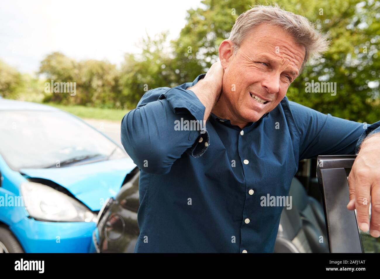 Mature Male Motorist With Whiplash Injury In Car Crash Getting Out Of Vehicle Stock Photo