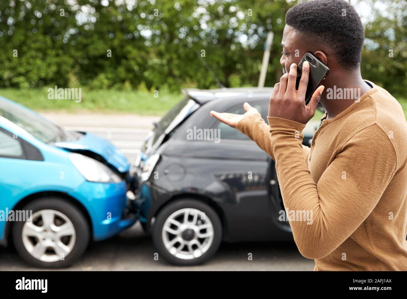 Male Motorist Involved In Car Accident Calling Insurance Company Or Recovery Service Stock Photo