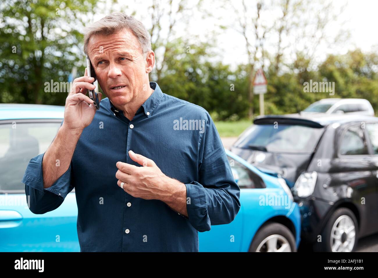 Mature Male Motorist Involved In Car Accident Calling Insurance Company Or Recovery Service Stock Photo