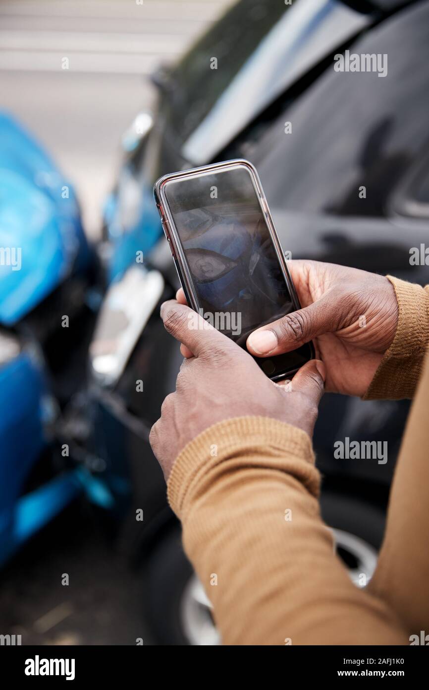 Male Motorist Involved In Car Accident Taking Picture Of Damage For Insurance Claim Stock Photo