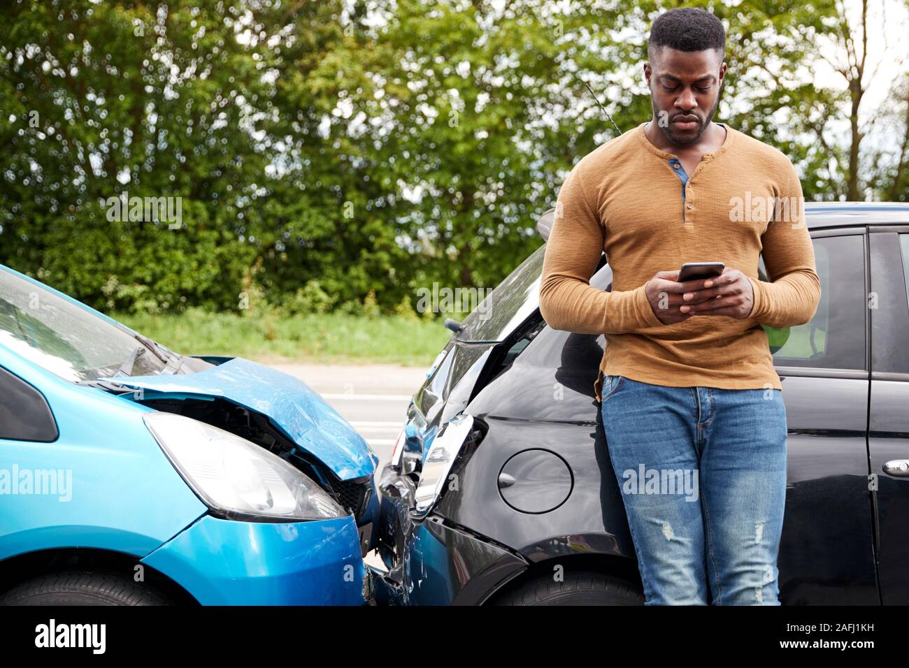 Male Motorist Involved In Car Accident Calling Insurance Company Or Recovery Service Stock Photo