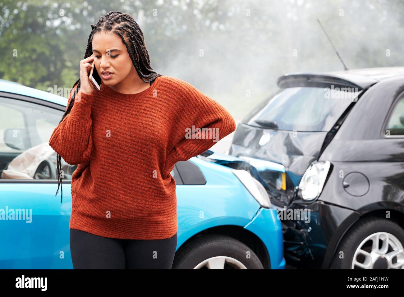 Female Motorist Involved In Car Accident Calling Insurance Company Or Recovery Service Stock Photo