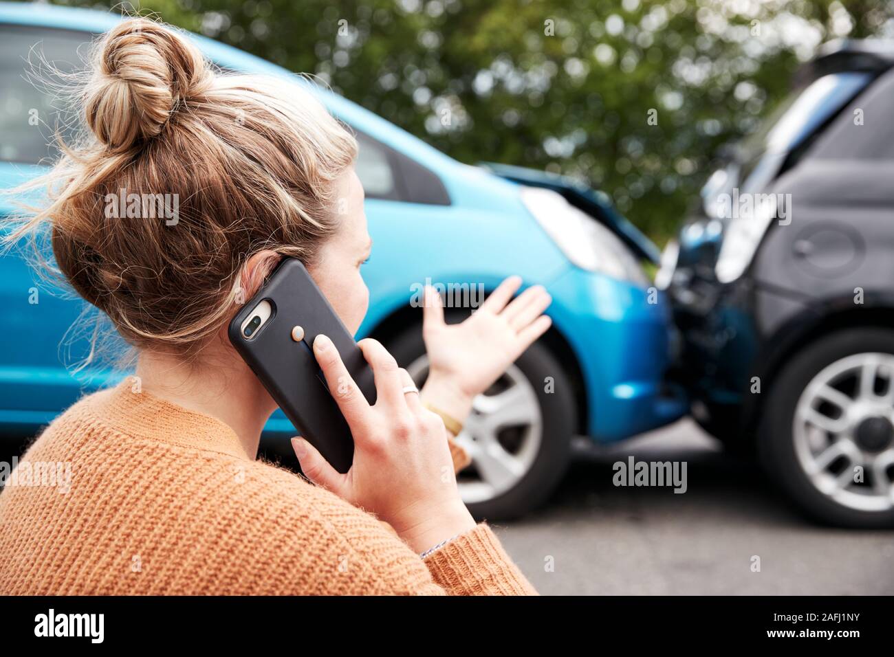 Female Motorist Involved In Car Accident Calling Insurance Company Or Recovery Service Stock Photo