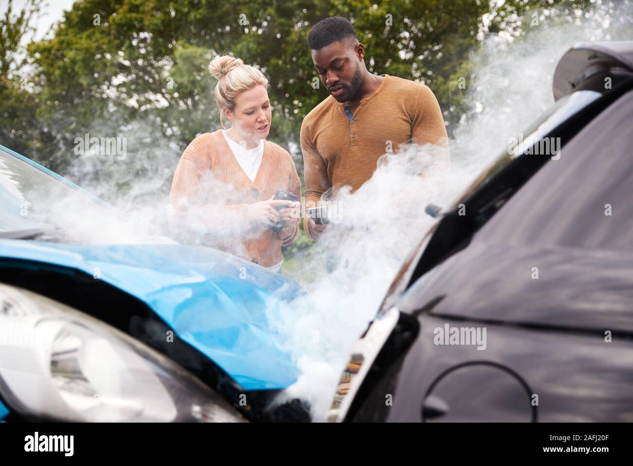 Two Motorists Swapping Insurance Details On Mobile Phone After Car Crash Stock Photo