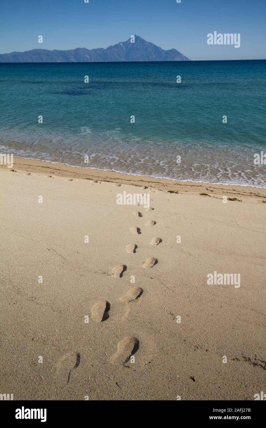 footprints in the sand, in the distance is Mount Athos Stock Photo