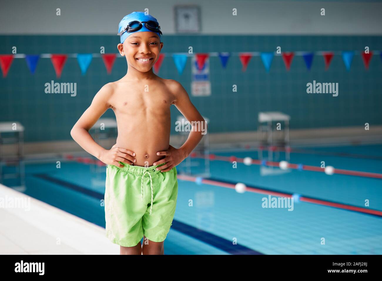 Portrait Of Boy Standing By Edge Of Swimming Pool Ready For Lesson Stock Photo