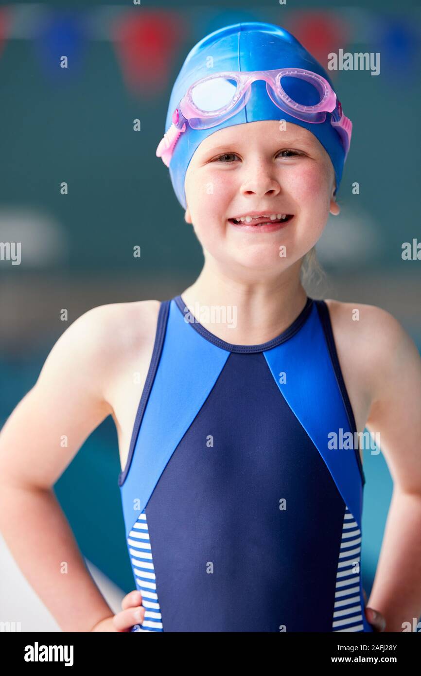 Portrait Of Girl Standing By Edge Of Swimming Pool Ready For Lesson Stock Photo