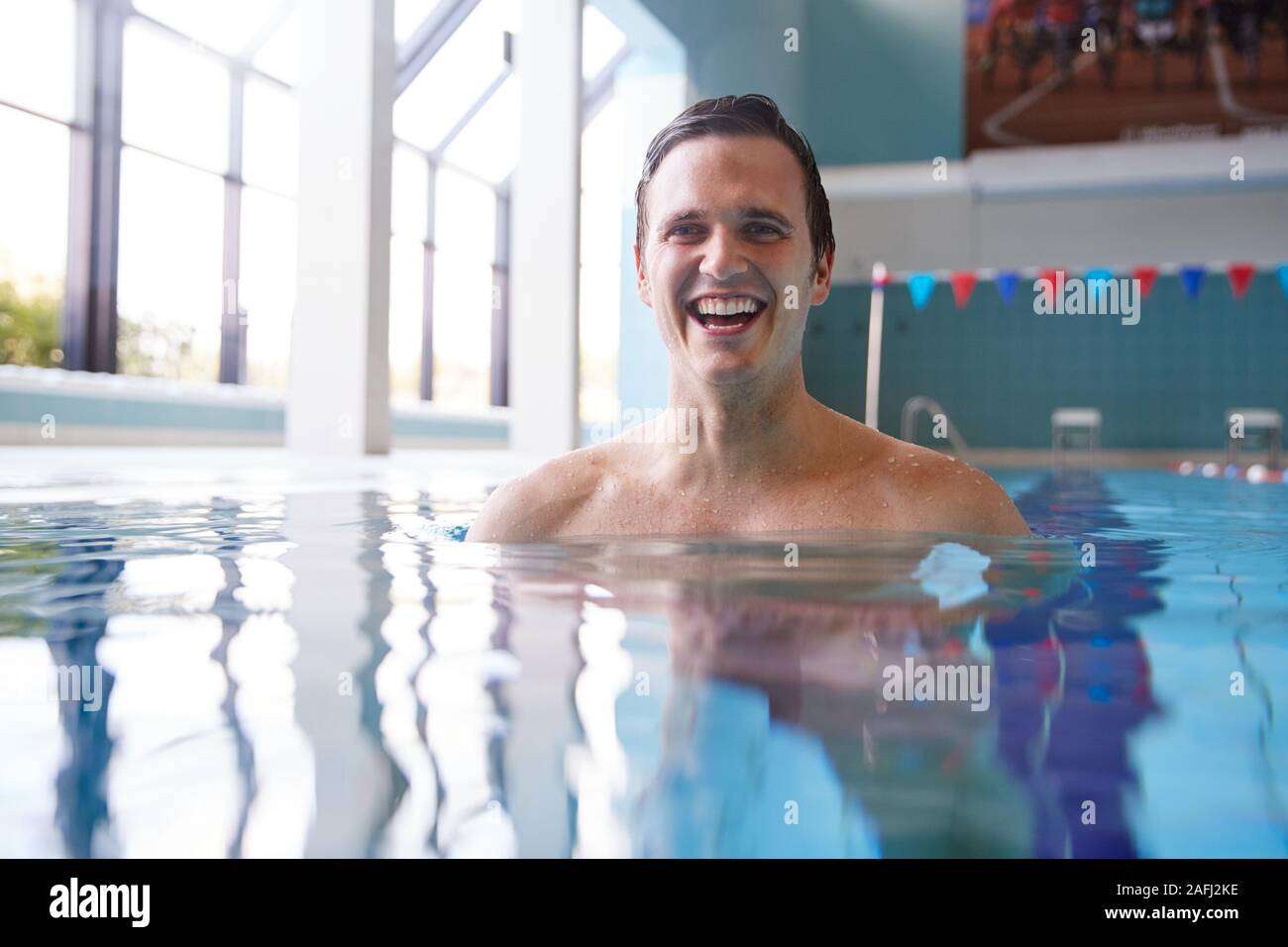 Portrait Of Male Swimmer Warming Up In Swimming Pool Stock Photo