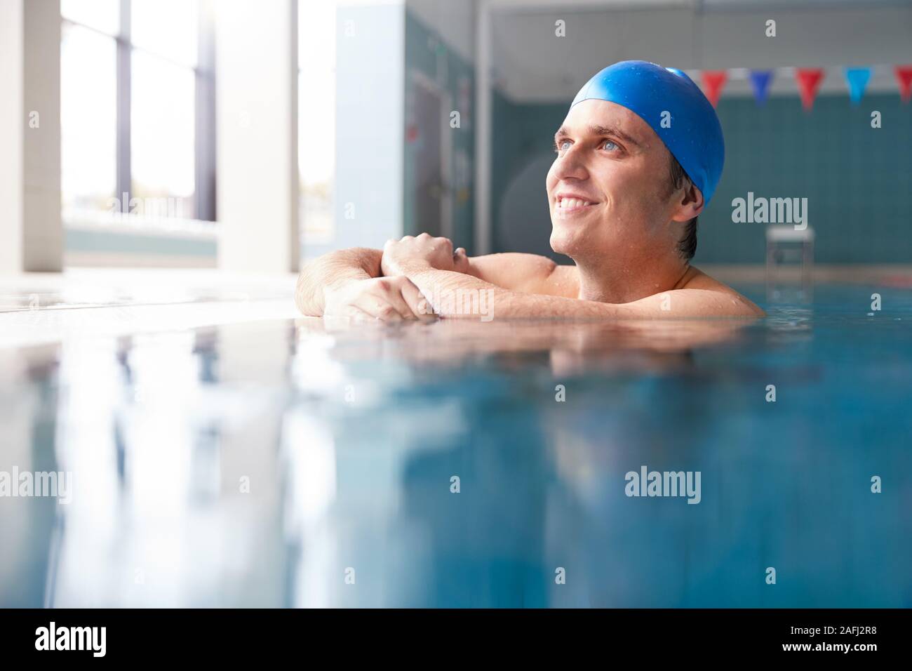 Male Swimmer Wearing Hat And Goggles Training In Swimming Pool Stock Photo