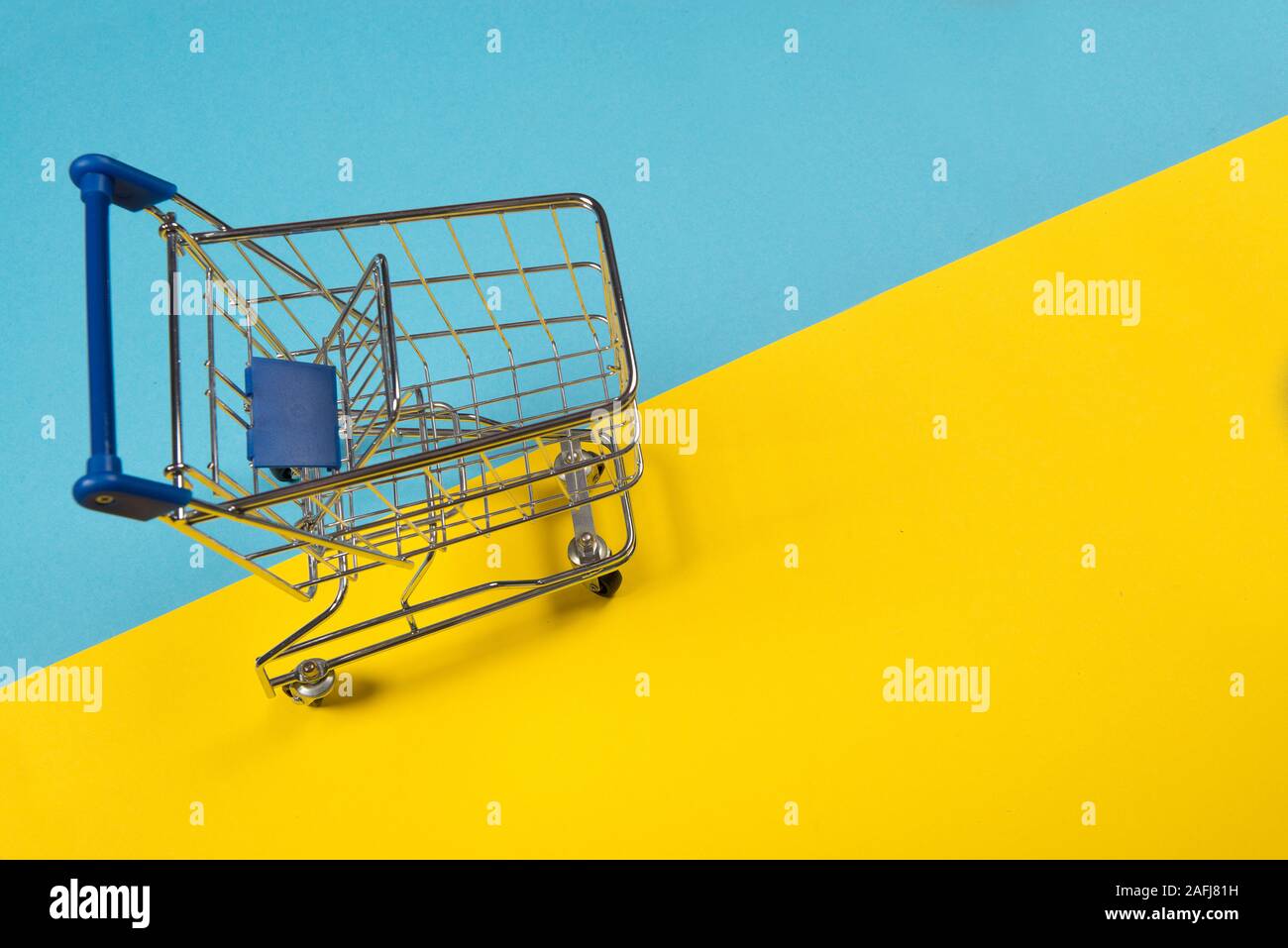 Empty push cart seen from an high angle on a blue and yellow background as a concept for