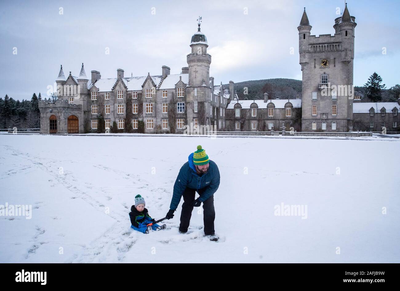 Geraint Stone pulls his two-year-old son Arthur on his sledge across the snow-covered lawn in front of Balmoral Castle, Royal Deeside. The Met Office has issued a yellow weather warning for ice and snow across Scotland. Stock Photo