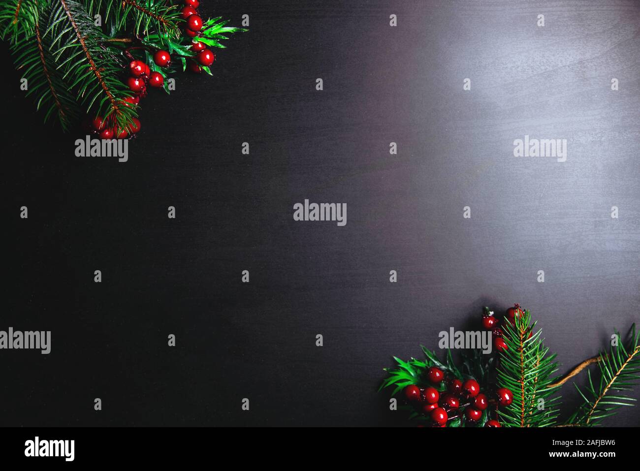 Christmas decoration with fir branches and red berries on a dark ...