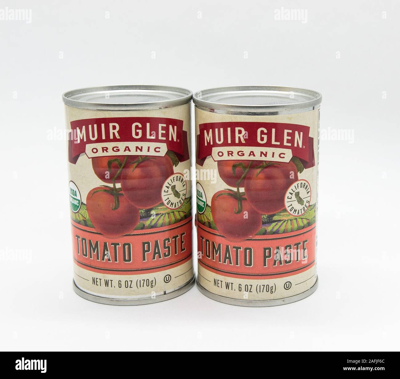 New York, 12/8/2019: Two cans of Muir Glen tomato paste stand against white background. Stock Photo