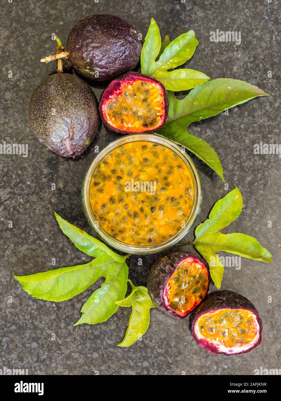 Lay flat composition showing Passion fruit, whole and sliced, Passion Fruit pulp and Leaves Stock Photo