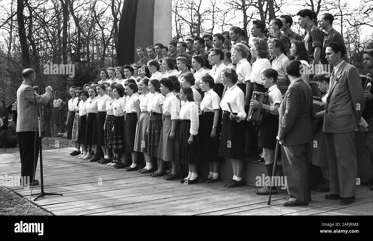 School choir of the Oberschule Fuerstenwalde (Choir director Wilhelm Koch, right with stick Heinz Weissleder) at the city park Fuerstenwalde on May 1. during a performance. Stock Photo