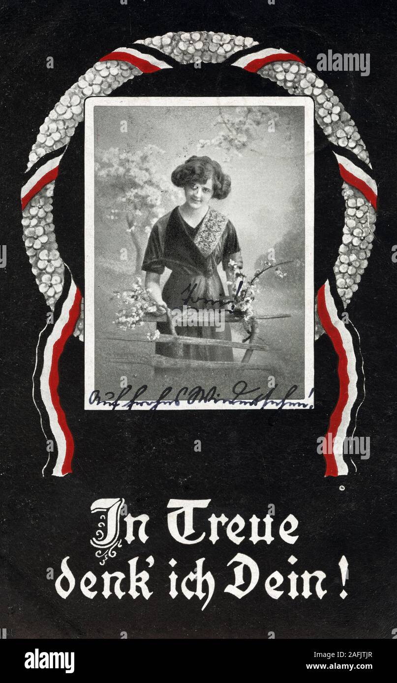 Postcard: 'In treue denk' ich Dein' (Devotedly thinking of you) with postmark from 1917. Picture shows a wreath with the colours of the German Empire and a woman at a fence with flowers. Stock Photo