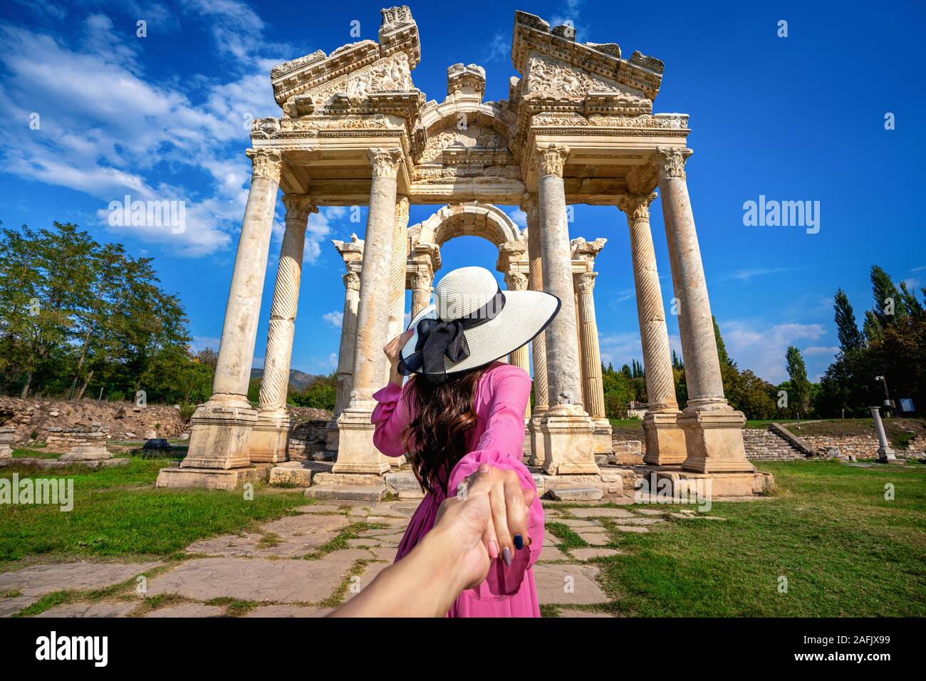 Women tourists holding man's hand and leading him to Aphrodisias ancient city in Turkey. Stock Photo